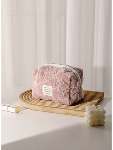 Pink corduroy makeup bag with white lace floral embroidery on wooden tray
