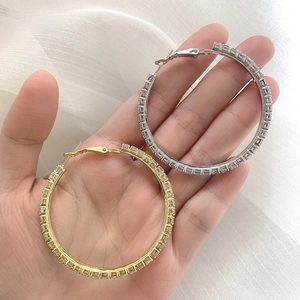 Macro shot of gold and silver hoop earrings with rectangular cubic zirconia accents