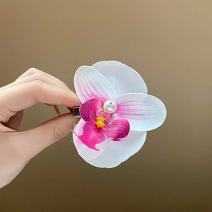 Detailed close-up of a realistic white orchid hair claw clip with a central pearl accent
