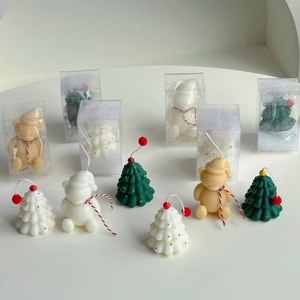 Macro detail of mini hand-painted Christmas tree and bear scented candles in gift packaging