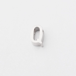 Macro shot of polished silver titanium steel letter Q bead with a smooth mirror finish