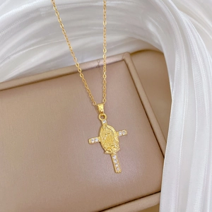 Close-up of gold-tone cross pendant with central relief portrait and small crystals