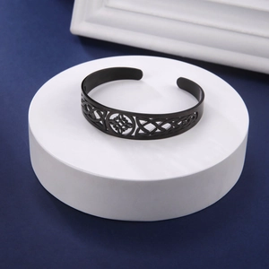 Close-up of black cutout cuff bracelet featuring a Celtic knot on a display stand