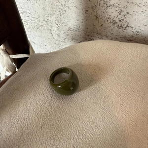 Minimalist olive green oval resin ring with thick polished finish on linen fabric