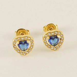 Détail de boucles d'oreilles cœur dorées avec pierre bleue et zircons brillants