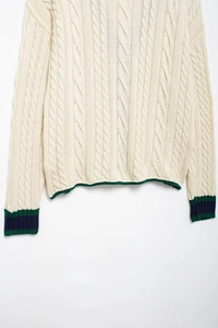Detailed view of cable knit pattern with green and blue striped ribbed cuffs
