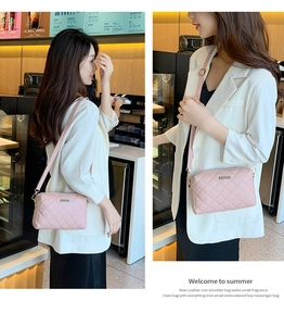 Detail view of a pink quilted crossbody bag with a metallic plaque on white blazer