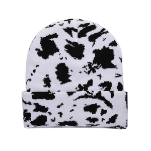 Winter knitted beanie hat featuring a black and white cow print pattern for women