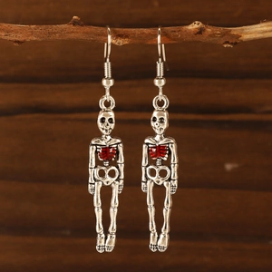 Gothic silver skull earrings with red heart accents hanging on a vintage branch