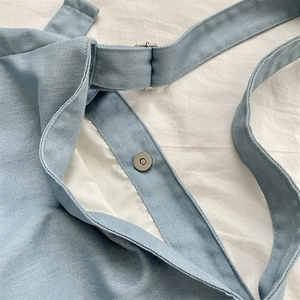 Detail of light blue tie-dye canvas tote with silver magnetic buckle and sturdy stitching