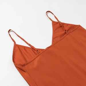 Detail of V-neckline and adjustable straps on orange satin dress with sleek metal buckles