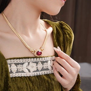 Close-up of vintage snake chain with an oval ruby pendant and crystal accents on neck