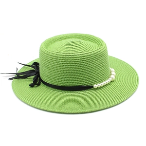 Dettaglio del cappello boater verde chiaro con nastro nero e perle bianche eleganti
