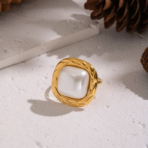 Detail of vintage gold ring with square pearl on a textured white background