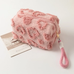Close-up of pink plush makeup bag featuring 3D embossed heart texture and soft fabric