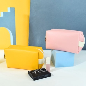 Detail of yellow and pink PU leather cosmetic bags with white zippers and strap handles