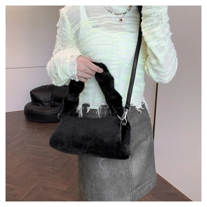Detail of black faux fur shoulder bag with plush texture and leather strap for autumn
