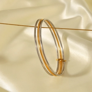 Close-up of three-ring interlocking bangle in gold and silver finish on silk