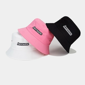 Vue détaillée de trois bobs en coton blanc, rose et noir avec broderie Awesome élégante