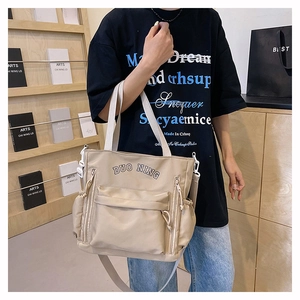 Detail view of beige canvas tote bag with multi-pocket design and Duo Ning branding