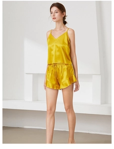 Close-up of golden silk pajama set featuring a V-neck camisole and ruffled drawstring shorts
