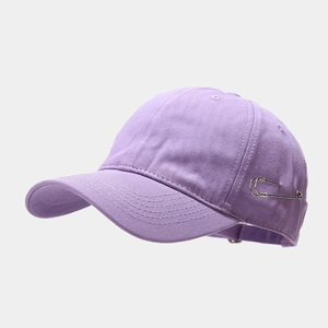 Close-up of purple cotton baseball cap featuring unique oversized silver safety pin detail