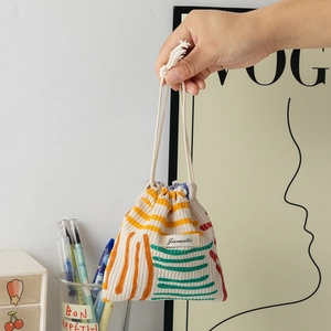 Detail of solid corduroy drawstring storage bag with geometric stripes and woven label