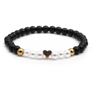 Minimalist beaded bracelet with black and white pearls and a golden heart charm pendant