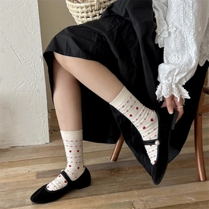 Détail de chaussettes en coton à motif cœur avec chaussures en velours et perles