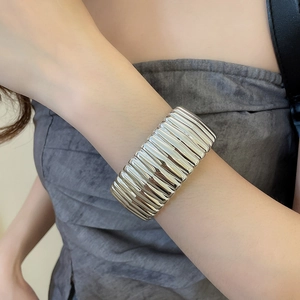 Detailed view of silver pleated metal cuff bracelet with vertical texture on model wrist