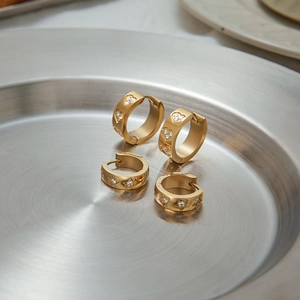 Detailed view of gold stainless steel huggie earrings with heart and star zircon patterns