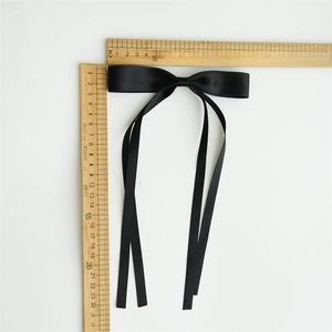 Detail view of large black satin bow hair clip with measurements showing 14cm width