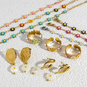 Detailed flat lay of golden stainless steel daisy bracelet, ring, and earrings set
