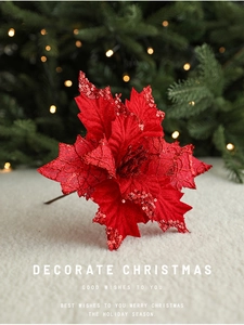 Detail of red sequined Christmas flower on white fur base with warm bokeh background