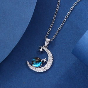 Detailed view of silver moon pendant with blue nebula sphere and sparkling stars