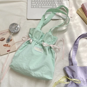 Detail of mint green canvas tote bag featuring pink ribbon bows and drawstrings