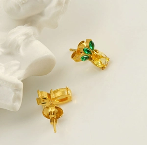 Detail of 18k gold plated stainless steel pineapple earrings with yellow and green zircons