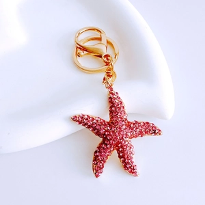 Detailed view of pink rhinestone starfish keychain with gold lobster clasp on white base