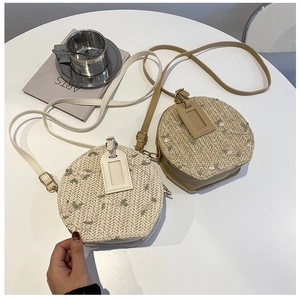 Detail view of round straw crossbody bags with delicate embroidered floral patterns