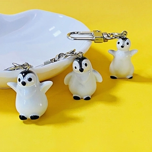 Close-up of cute resin penguin keychains on a heart-shaped plate with a yellow background