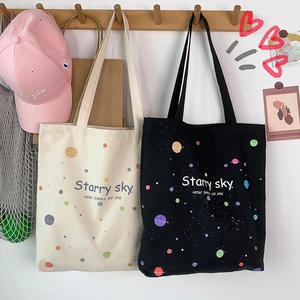 Détail de sacs fourre-tout en toile imprimés ciel étoilé en noir et crème sur un mur