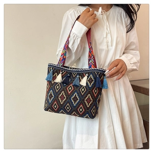 Detail of ethnic tote bag showing geometric patterns, tassel decor, and woven strap