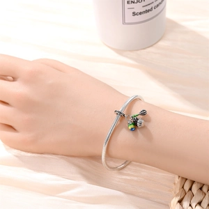 Silver snake chain bracelet with colorful enamel charms and whisk pendant on wrist