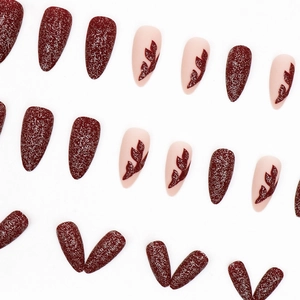 Deep red glitter and almond-shaped leaf print press-on nails set on white background
