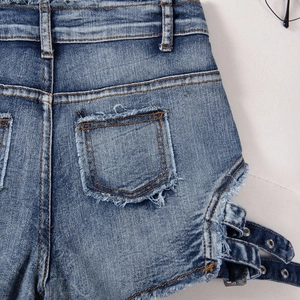 Detalle de la hebilla lateral calada y costuras de los bolsillos en shorts vaqueros