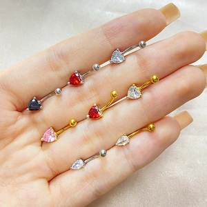 Hand holding heart and pear shaped zircon eyebrow rings in gold and silver metal