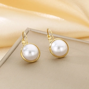 Detail shot of round white pearl earrings with elegant gold metallic borders