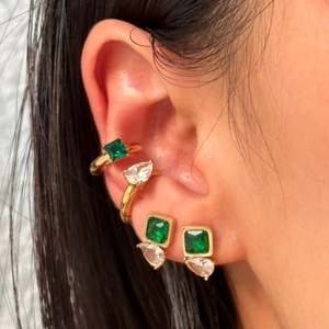 Close-up of vintage gold ear cuffs with emerald-cut green and pear-shaped zircon stones