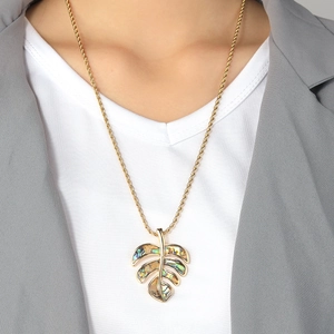 Golden monstera leaf necklace set with colorful abalone shell inlay on a female model