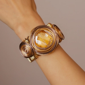 Macro shot of handcrafted woven gold wire cuff with a large faceted yellow crystal stone